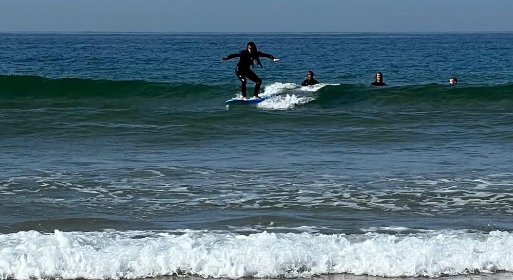 surf standing on a surfboard riding the waves in Tamraght