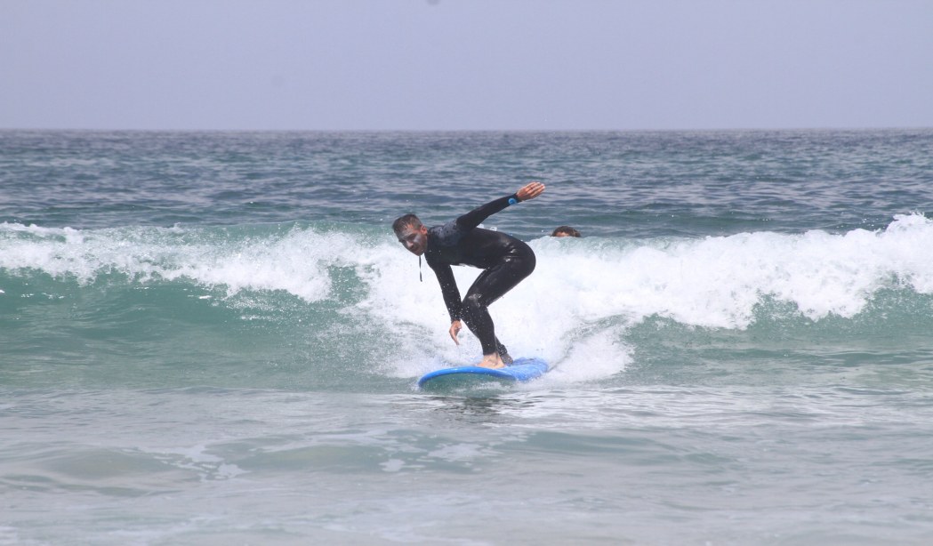 Surfer in waist-high waves showing surf conditions for beginners.